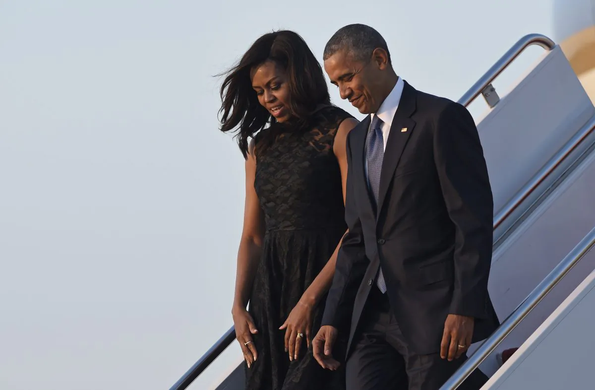First lady Michelle Obama tries to keep her dress from blowing as she walks down the steps of Air Force One with President Barack Obama at Andrews Air Force Base in Md., Tuesday, July 12, 2016. The Obama's are returning from Dallas where they attended an interfaith memorial service for the fallen police officers and members of the Dallas community. (AP Photo/Susan Walsh)