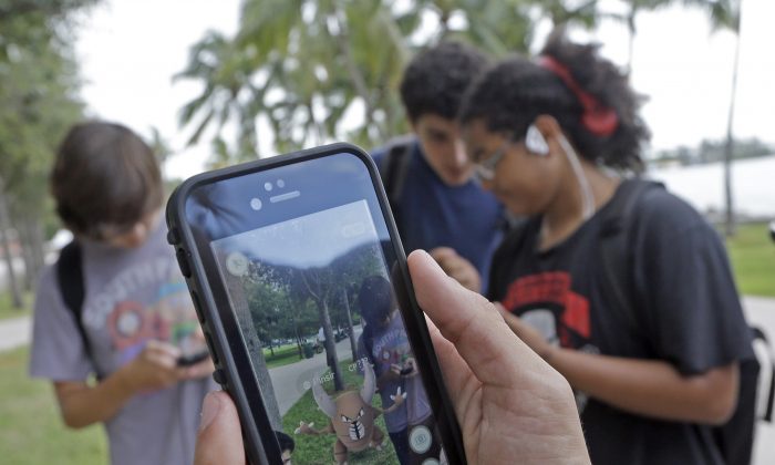FILE - In this Tuesday, July 12, 2016, file photo, Pinsir, a Pokemon, is found by a group of Pokemon Go players at Bayfront Park in downtown Miami. The "Pokemon Go" craze has sent legions of players hiking around cities and battling with "pocket monsters" on their smartphones. (AP Photo/Alan Diaz, File)