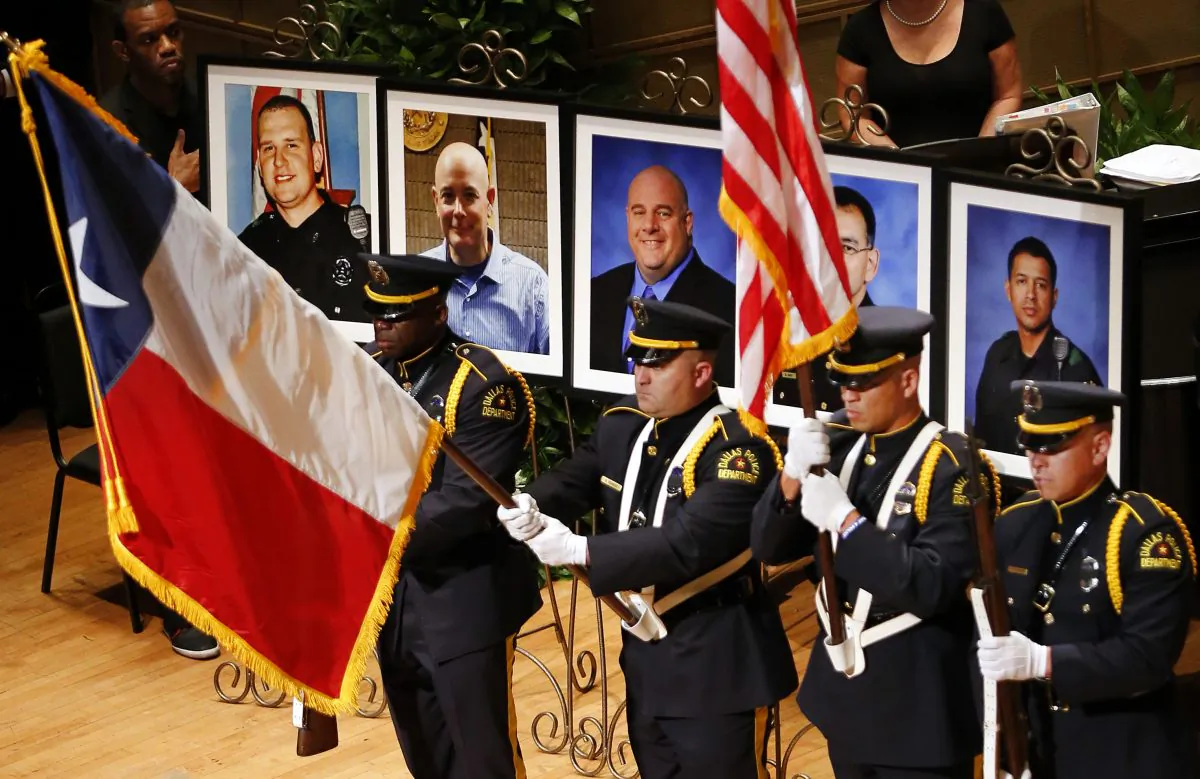 The Dallas Police color guard presents the colors before the photos of five fallen officers being remembered during an interfaith memorial service at the Morton H. Meyerson Symphony Center in Dallas, Tuesday, July 12, 2016. The Dallas police officers and one Dallas Area Rapid Transit (DART) officer who were gunned down in downtown Dallas at a protest rally are, from left, Dallas PD officer Michael Krol, DART officer Brent Thompson, Dallas police Sr. Cpl. Lorne Ahrens, Dallas police Sgt. Michael Smith, and Dallas police Officer Patrick Zamarripa. (Tom Fox/The Dallas Morning News via AP)