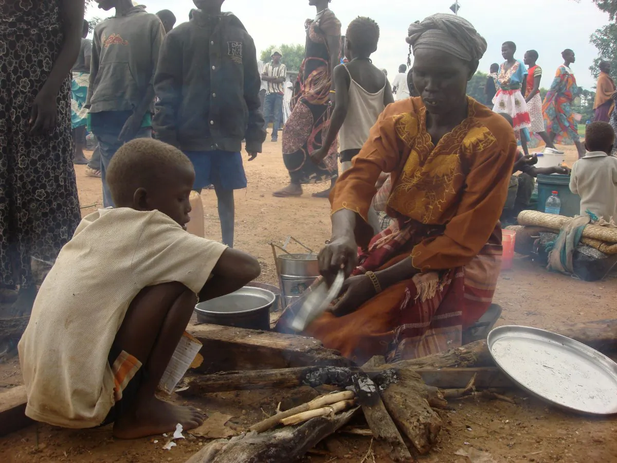A woman prepares food as displaced women, men and children gather, in Juba, South Sudan at the UN compound in Tomping area on July 12, 2016. ( Beatrice Mategwa/UNMISS via AP)