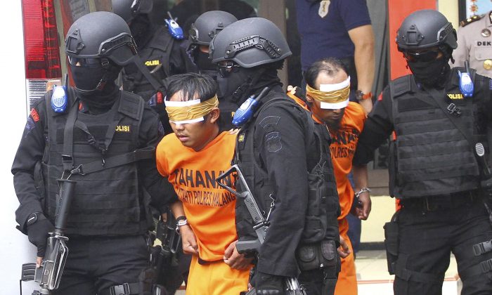 FILE - In this Feb. 21, 2016, file photo, Indonesian police officers escort suspected militants arrested in raids in Malang, East Java, Indonesia. Terrorism experts say the threat from the militants, spread across predominantly Muslim Indonesia, Malaysia and the southern Philippines, should not be underestimated and they could be transformed into a more dangerous force by training and leadership. (AP Photo/H.Y. Prabowo, File)