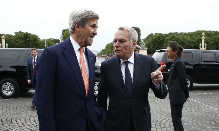 French Foreign Minister Jean-Marc Ayrault, right, welcomes U.S Secretary of State John Kerry on the Champs Elysees avenue before the Bastille Day Parade in Paris, Thursday, July 14, 2016. (AP Photo/Thibault Camus, Pool)