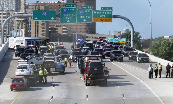 State troopers and police clear the Interstate 35W freeway where protesters blocked the highway leading into Minneapolis over the Mississippi River bridge during rush hour Wednesday, July 13, 2016, in Minneapolis as protests continue over the shooting death by police of Philando Castile. The protesters were arrested. (AP Photo/Jim Mone)