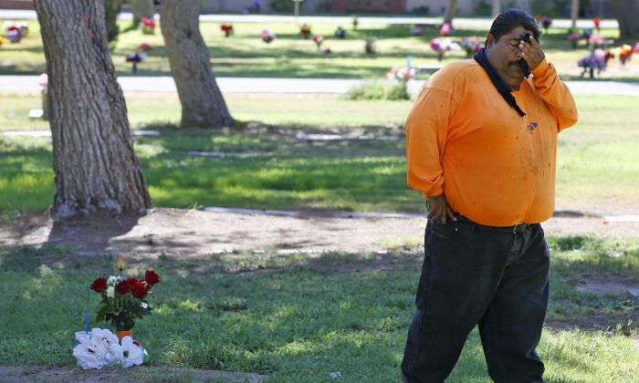 Margarito Castro, father of Manuel "Manny" Castro Garcia, 19, pauses for a moment as he visits his son's grave at a cemetery Thursday, July 14, 2016, in Phoenix. The teen was killed in June, and is one of a growing number of victims associated with a serial killer according to police. (AP Photo/Ross D. Franklin)