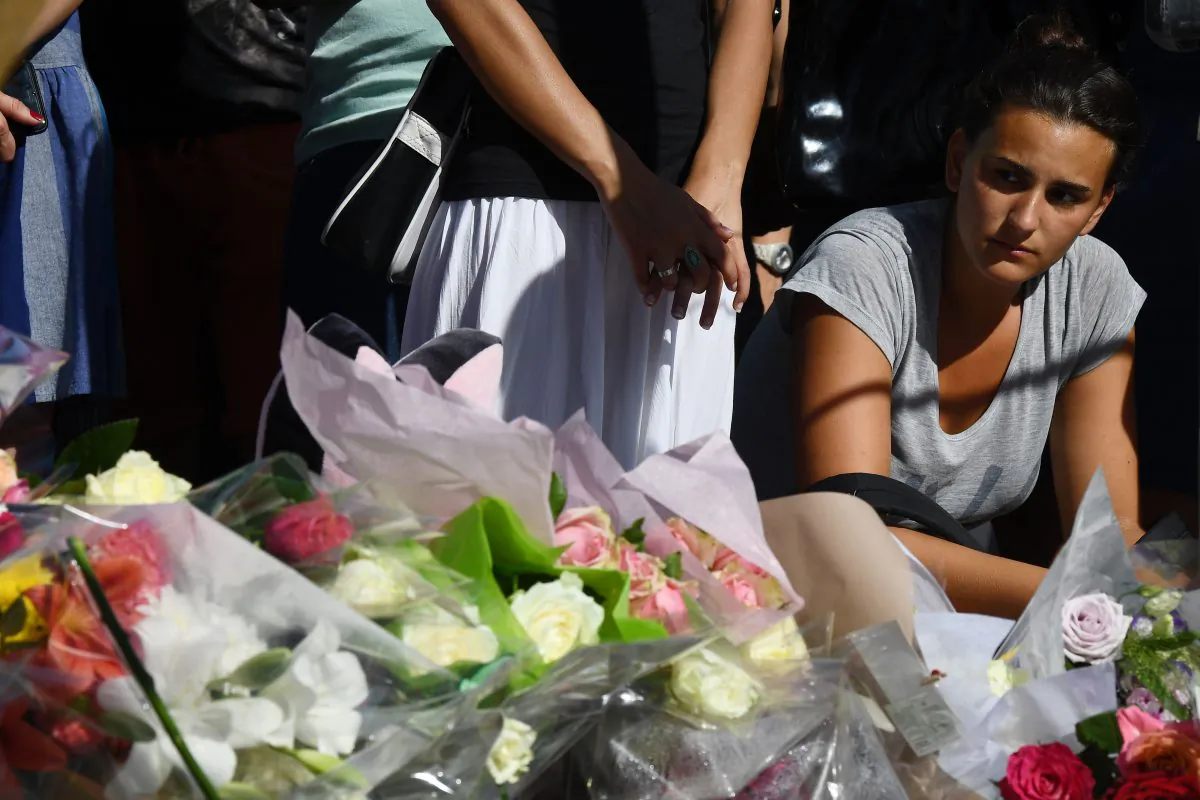 A woman at the makeshift memorial where people laid flowers to pay tribute to the victims the day after a man smashed a truck into a crowd of revelers celebrating Bastille Day, killing at least 84 people, on July 15, 2016. (ANNE-CHRISTINE POUJOULAT/AFP/Getty Images)
