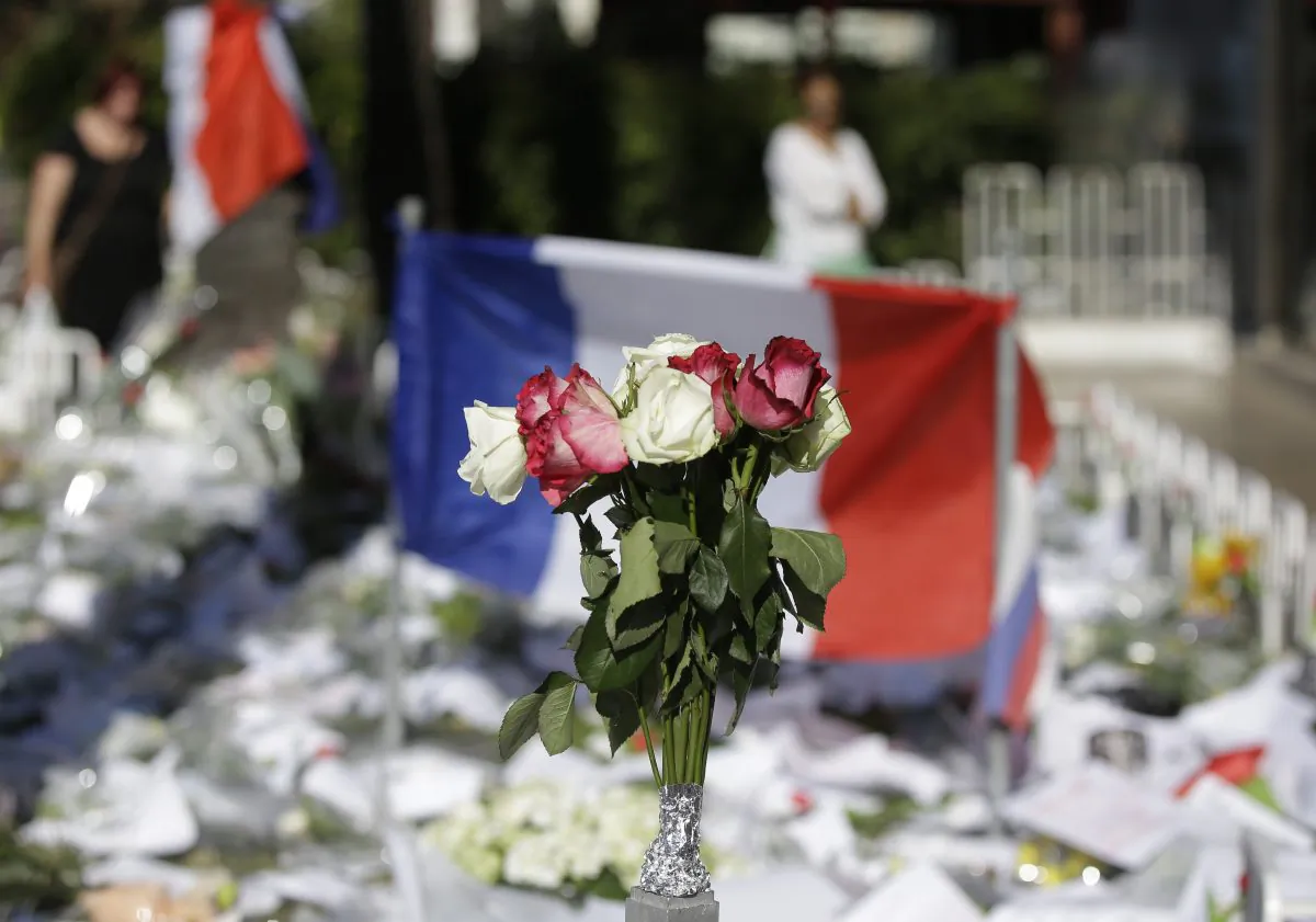 Floral and papers tributes are laid with a French flag near the scene of a truck attack in Nice, southern France, on July 16, 2016. (AP Photo/Luca Bruno)