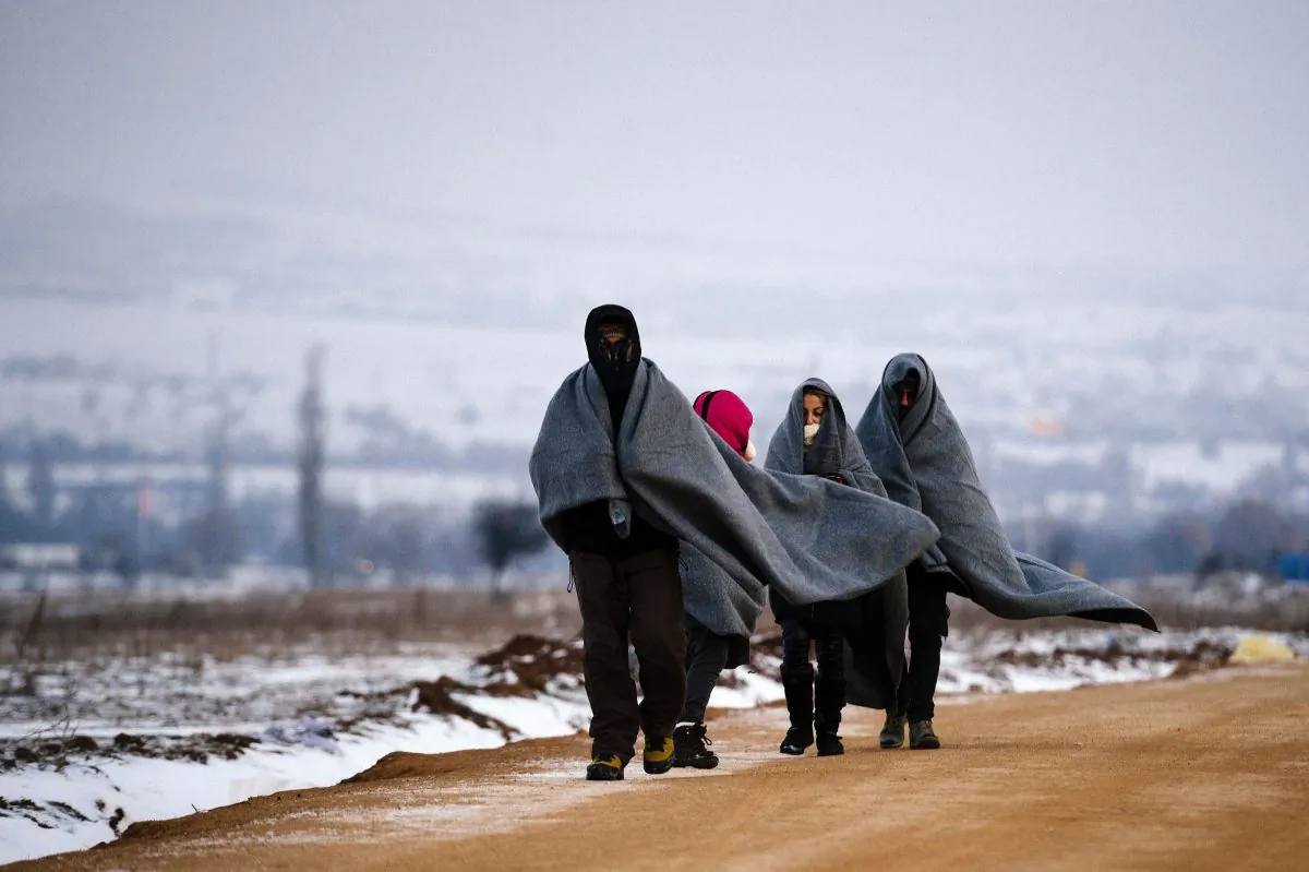 Migrants and refugees use their sleeping blankets to keep warm as they walk along snow-covered fields after crossing the Macedonian-Serbian border near the village of Miratovac on Jan. 18, 2016. (Dimitar Dilkoff/AFP/Getty Images)