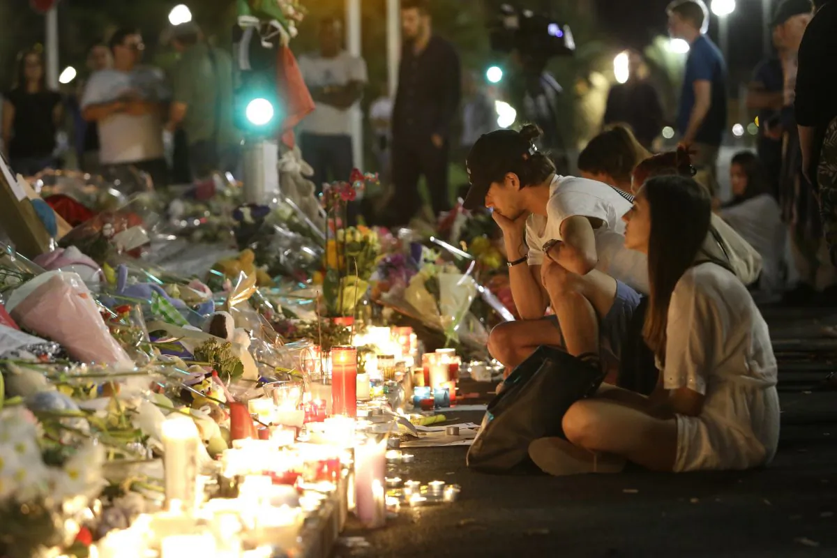 People gather at a makeshift memorial to honor the victims of an attack, near the area where a truck mowed through revelers in Nice, southern France, on July 16, 2016. (AP Photo/Claude Paris)