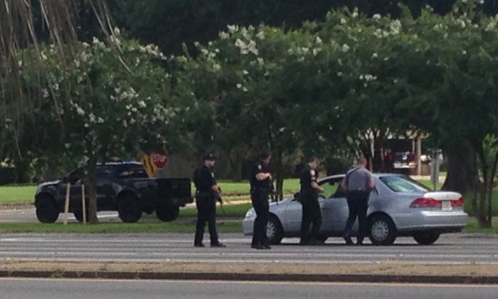 Authorities talk to the driver of a car near an area where several officers were shot while on duty less than a mile from police headquarters, Sunday, July 17, 2016, in Baton Rouge, La. (AP Photo/Mike Kunzelman)
