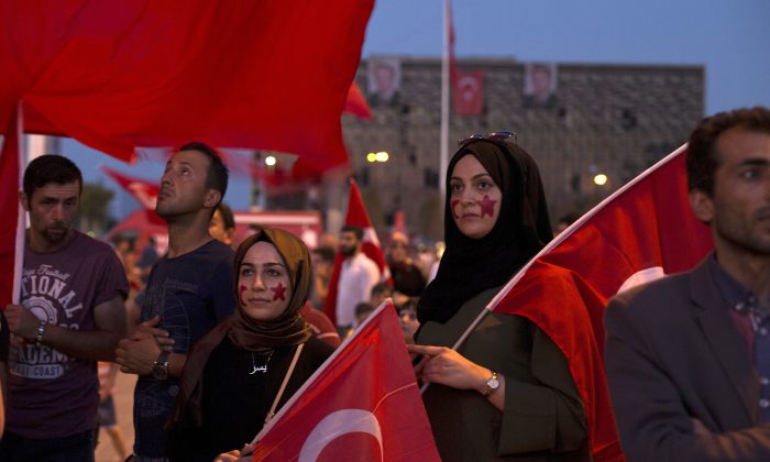 Protesters hold Turkish flags as they gather in Taksim Square in Istanbul, Sunday, July 17, 2016. (AP Photo/Petros Giannakouris)