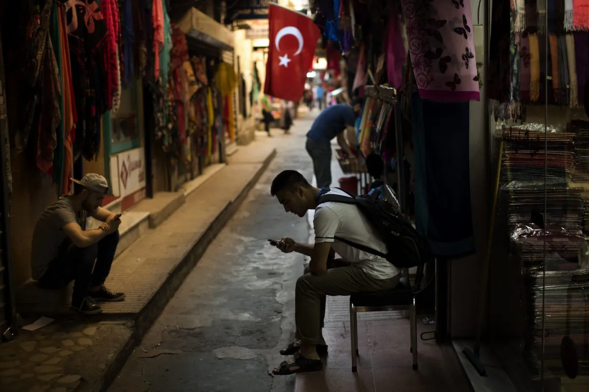 Sellers wait for customers as they look at their phones in central Istanbul, Monday, July 18, 2016. Warplanes patrolled Turkey's skies days after a failed coup, officials said Monday, in a sign that authorities feared that the threat against the government was not yet over. (AP Photo/Emilio Morenatti)