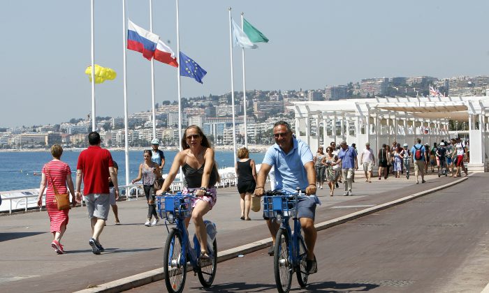 People ride bicycles along the Promenade des Anglais in Nice, southern France, Tuesday, July 19, 2016. (AP Photo/Claude Paris)