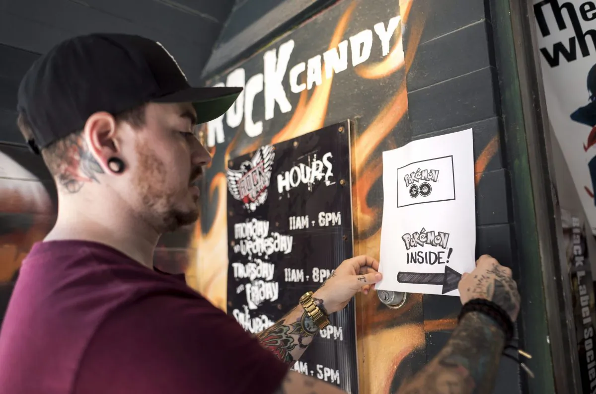 Jeff Powers, assistant manager at Rock Candy Boutique, puts up a sign encouraging Pokemon Go players to play inside the store in Halifax on July 19, 2016.  (The Canadian Press/Darren Calabrese)