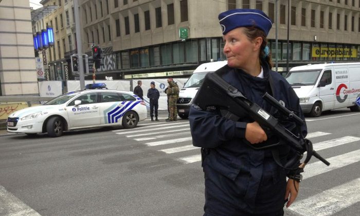An armed police officer stands guard near a blocked off street in downtown Brussels Tuesday June 21, 2016 after Belgian authorities took a man into custody following a pre-dawn security alert at a major shopping center. The security operation followed an alert about a suspicious package. (AP Photo/Virginia Mayo)