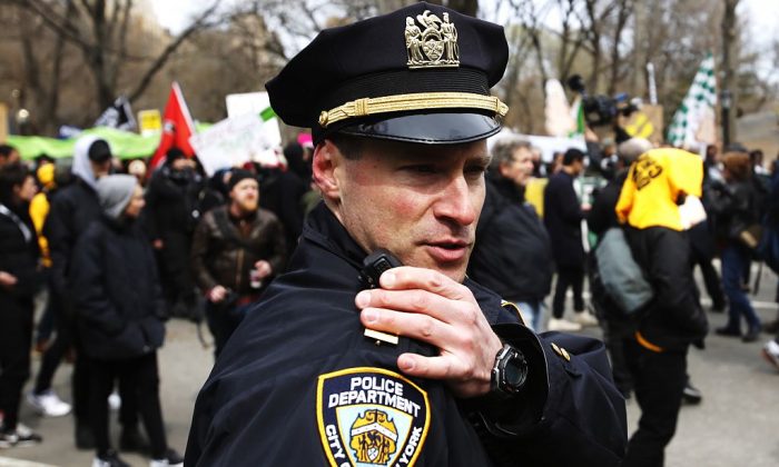 NEW YORK, NY - MARCH 19: An NYPD officer talks on his radio while people take part in a protest against Republican presidential candidate Donald Trump, on March 19, 2016 in New York City. People protest against Trump's policies which threaten the Immigration system and many of the Latino, Black, LGBT, Muslim, and other communities. (Photo by Eduardo Munoz Alvarez/Getty Images)
