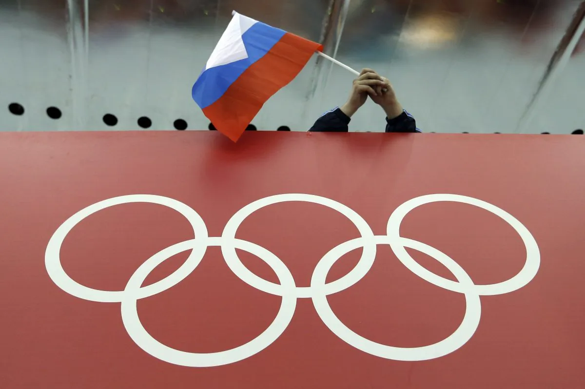 A Russian skating fan holds the country's national flag over the Olympic rings before the start of the men's 10,000-meter speedskating race at Adler Arena Skating Center during the 2014 Winter Olympics in Sochi, Russia, on Feb. 18, 2014. (David J. Phillip/AP Photo)