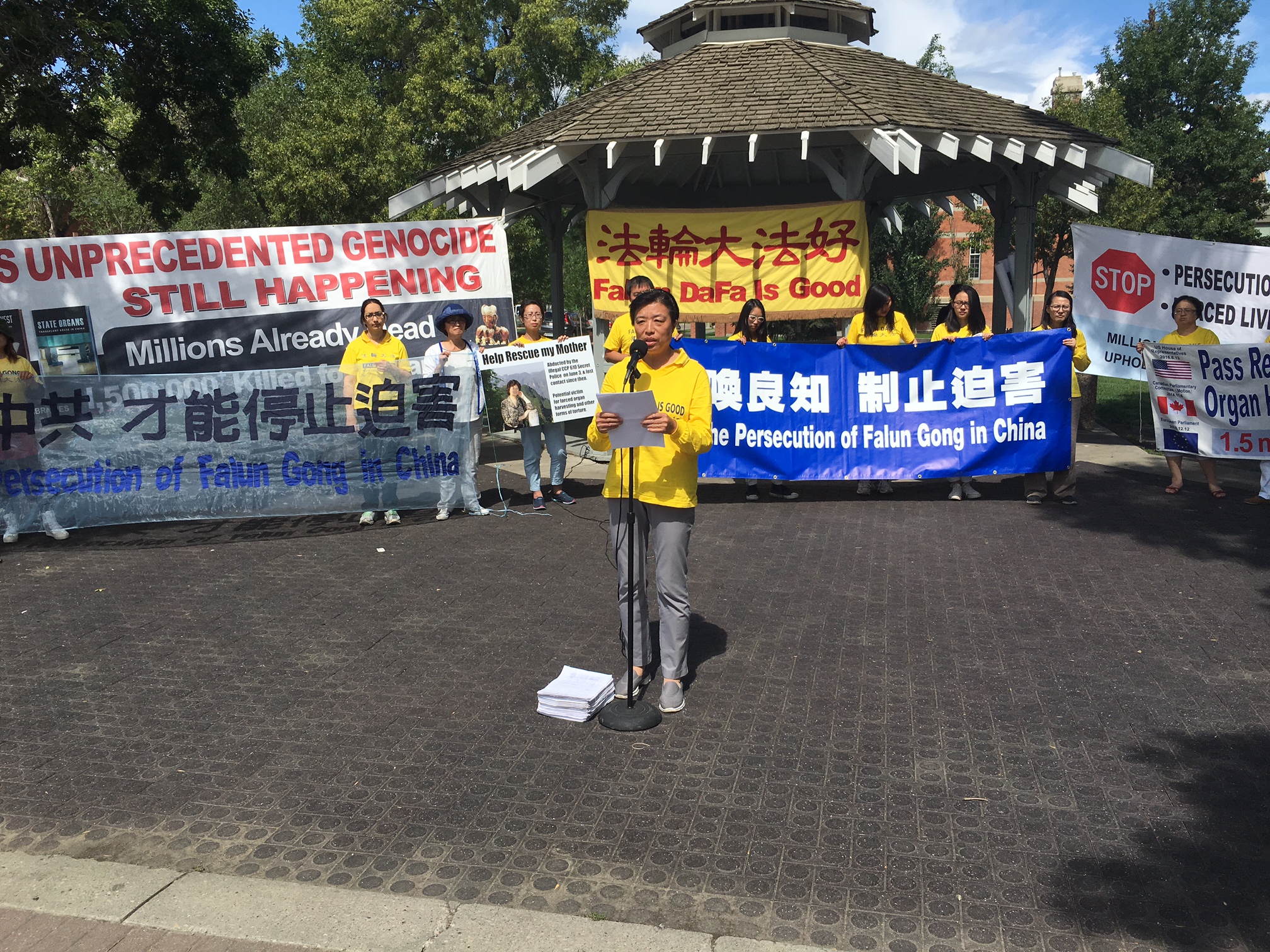 Minnan Liu speaks at a rally in Edmonton on July 23, 2016  to commemorate the 17th anniversary of the persecution of Falun Dafa in China. Liu presented the over 9,000 petitions signed by Edmontonians since last year to bring to justice the former Chinese leader Jiang Zemin who started the persecution on July 20, 1999. Behind her Hongyan Lu holds a sign asking for support to release her mother, Huixia Chen, who is currently detained in China for practicing Falun Dafa.  (Omid Ghoreishi/Epoch Times)