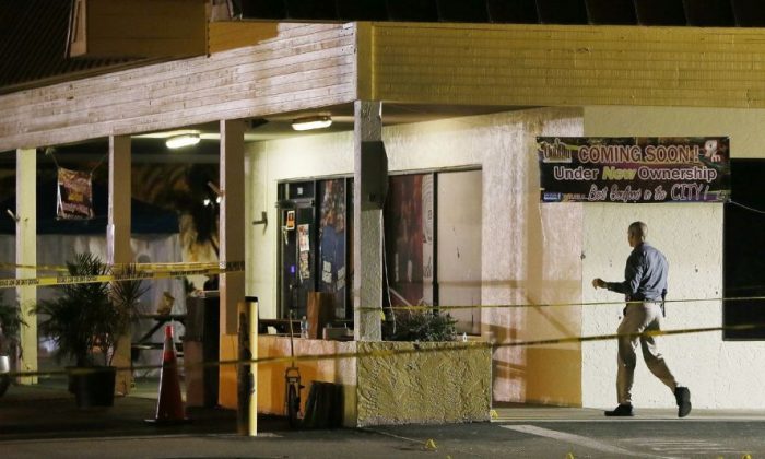 An investigator walks near the scene of a fatal shooting at Club Blu nightclub in Fort Myers, Fla., Monday, July 25, 2016. (Kinfay Moroti/The News-Press via AP)