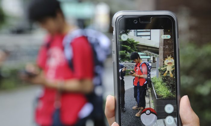 FILE - In this July 22, 2016 file photo, Japanese students play "Pokemon Go" in the street as its released in Tokyo. Japanese video game maker Nintendo Co. has sunk into a loss of 24.53 billion yen ($232 million) for the fiscal first quarter through June, 2016 despite the global success of the “Pokemon Go” augmented reality game. The result Wednesday, July 27, 2016, was worse than the 673 million yen ($6.4 million) profit forecast by analysts surveyed by FactSet. (AP Photo/Koji Sasahara, File)
