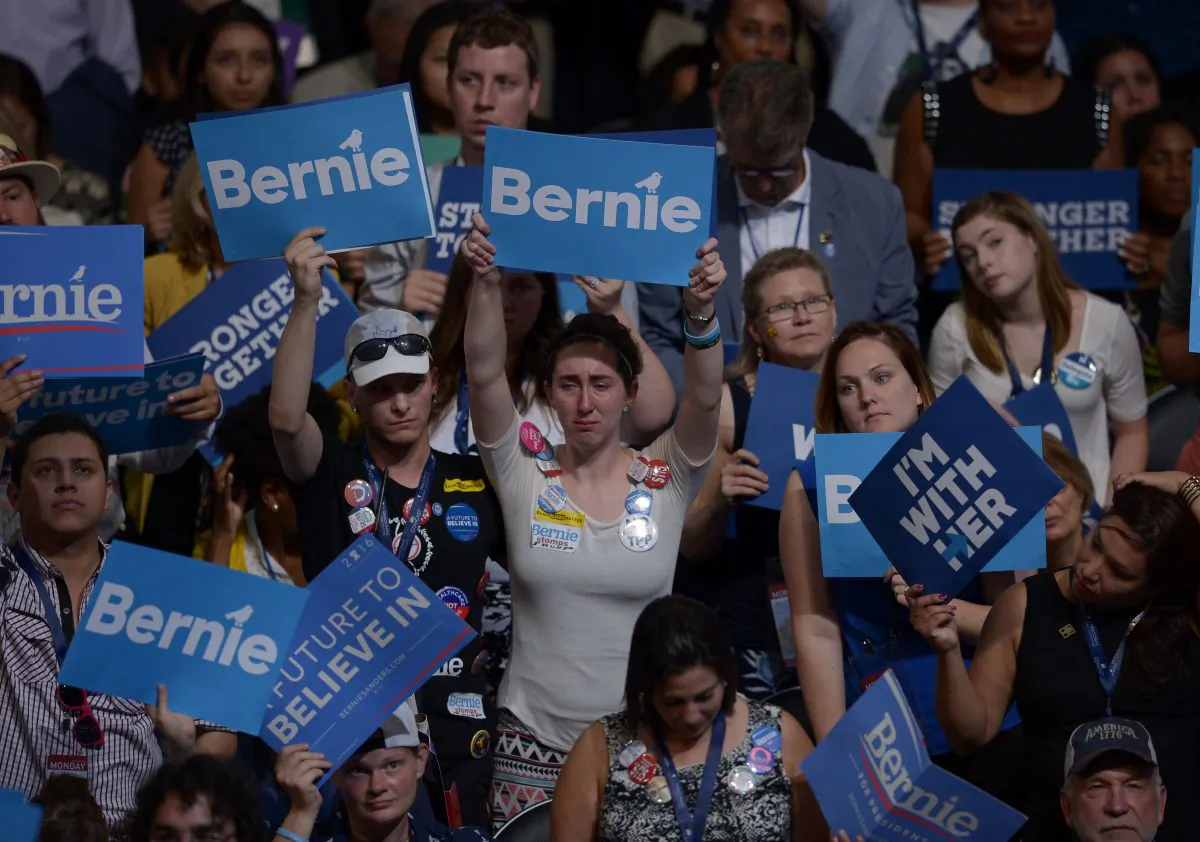 Supporters of Senator Bernie Sanders and Hillary Clinton hoist signs on Day 1 of the National Convention at the Wells Fargo Center in Philadelphia on July 25, 2016. (Brendan Smialowski/AFP/Getty Images)