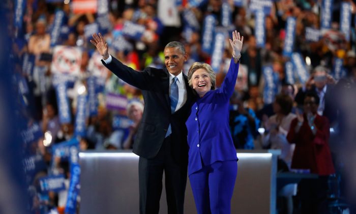 US President Barack Obama and Democratic presidential nominee Hillary Clinton acknowledge the crowd on the third day of the Democratic National Convention at the Wells Fargo Center, July 27, 2016 in Philadelphia, Pennsylvania. (Photo by Aaron P. Bernstein/Getty Images)