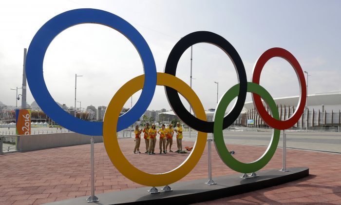Volunteers stand near a set of Olympic Rings at Olympic Park in Rio de Janeiro on July 29, 2016. (AP Photo/Patrick Semansky)
