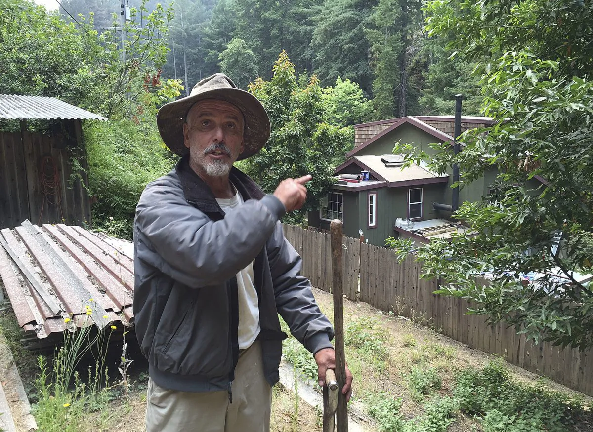 Resident Keith Bispo points to his house in the Palo Colorado community while interviewed in Big Sur, Calif., on July 29, 2016. Bispo stayed at his house the past week to protect he and his neighbors' properties after the area was evacuated. Lodge managers and cafe owners along California's dramatic Big Sur coast were looking Friday at a summer of jittery guests and cancelled bookings after fire officials warned that crews will likely be battling a wildfire raging in steep, forested ridges just to the north for another month. (AP Photo/Terry Chea)