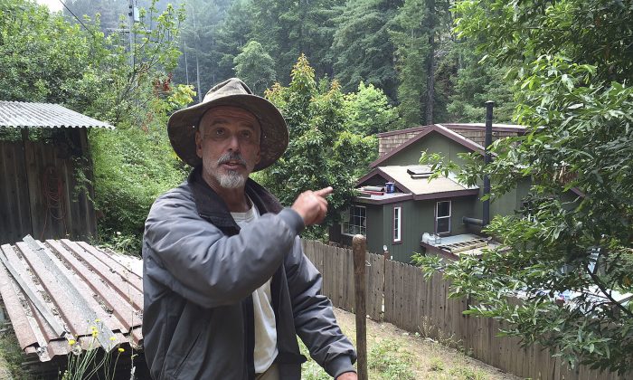 Resident Keith Bispo points to his house in the Palo Colorado community while interviewed in Big Sur, Calif., on July 29, 2016. Bispo stayed at his house the past week to protect he and his neighbors' properties after the area was evacuated. Lodge managers and cafe owners along California's dramatic Big Sur coast were looking Friday at a summer of jittery guests and cancelled bookings after fire officials warned that crews will likely be battling a wildfire raging in steep, forested ridges just to the north for another month. (AP Photo/Terry Chea)
