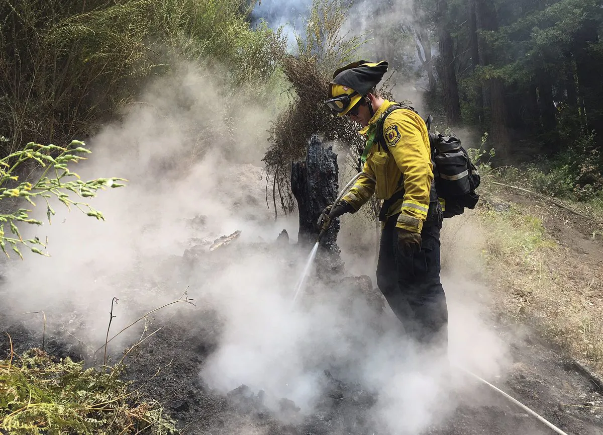 A firefighter extinguishes a spot fire in Big Sur, Calif., on July 29. (AP Photo/Terry/Chea)