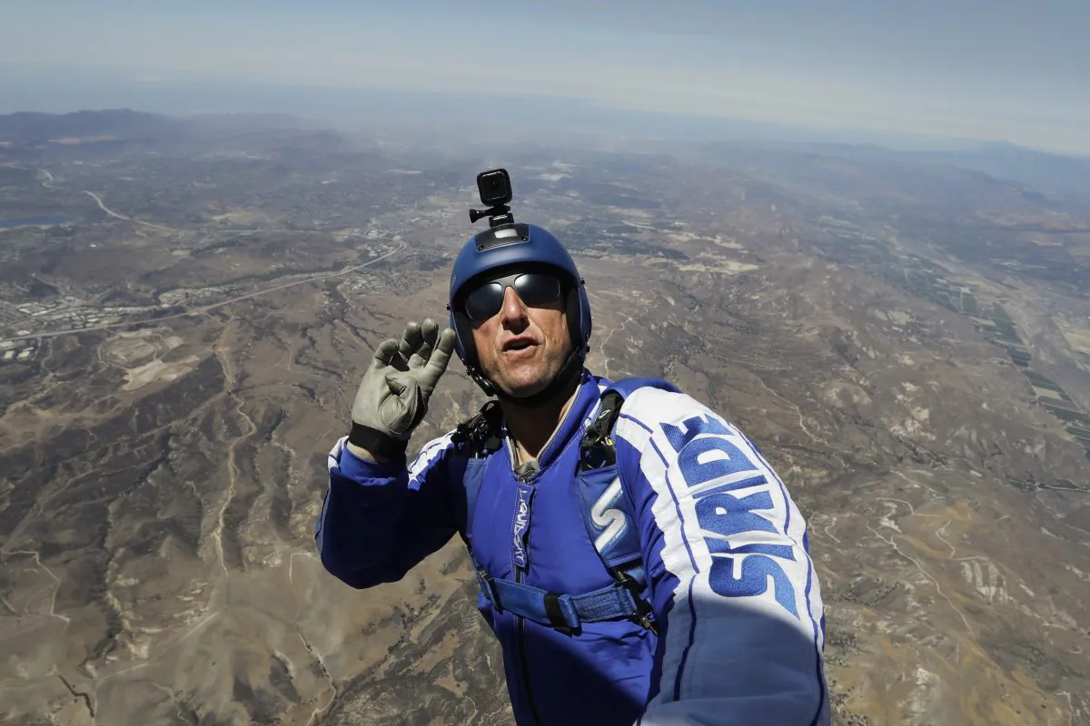 Skydiver Luke Aikins signals to pilot Aaron Fitzgerald as he prepares to jump from a helicopter in Simi Valley, Calif., on July 25, 2016. After months of training, this elite skydiver says he's ready to leave his chute in the plane when he bails out 25,000 feet over Simi Valley on Saturday. That's right, no parachute, no wingsuit, and no fellow skydiver with an extra one to hand him in mid-air. (AP Photo/Jae C. Hong)