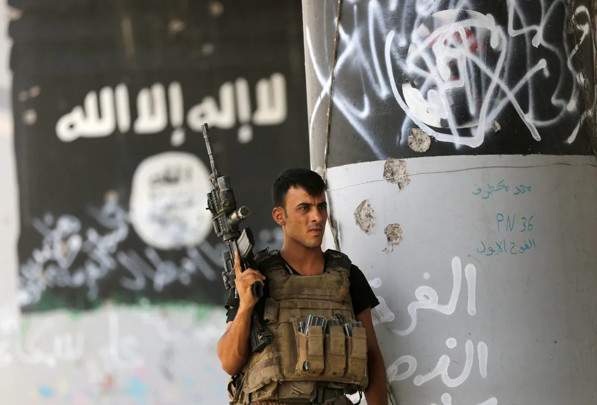 A member of Iraqi counterterrorism forces stands guard near Islamic State militant graffiti in Fallujah, Iraq, on June 27, 2016. (AP Photo/Hadi Mizban)