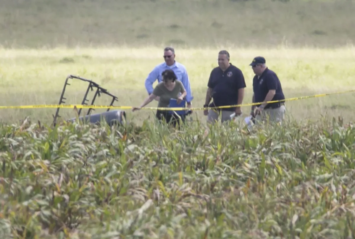 The partial frame of a hot air balloon is visible above a crop field as investigators comb the wreckage of a crash Saturday, July 30, 2016, in Central Texas near Lockhart, Texas. Authorities say the accident caused a "significant loss of life." (Ralph Barrera/Austin American-Statesman via AP)