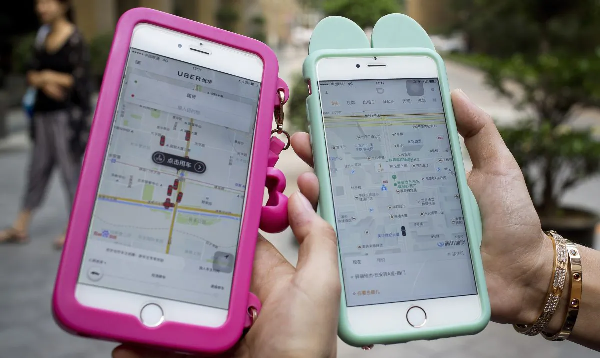 Smartphones show the ride-hailing apps Uber Technology Ltd., left, and Didi Chuxing at a residential compound in Beijing, on Aug. 1, 2016. (AP Photo/Andy Wong)