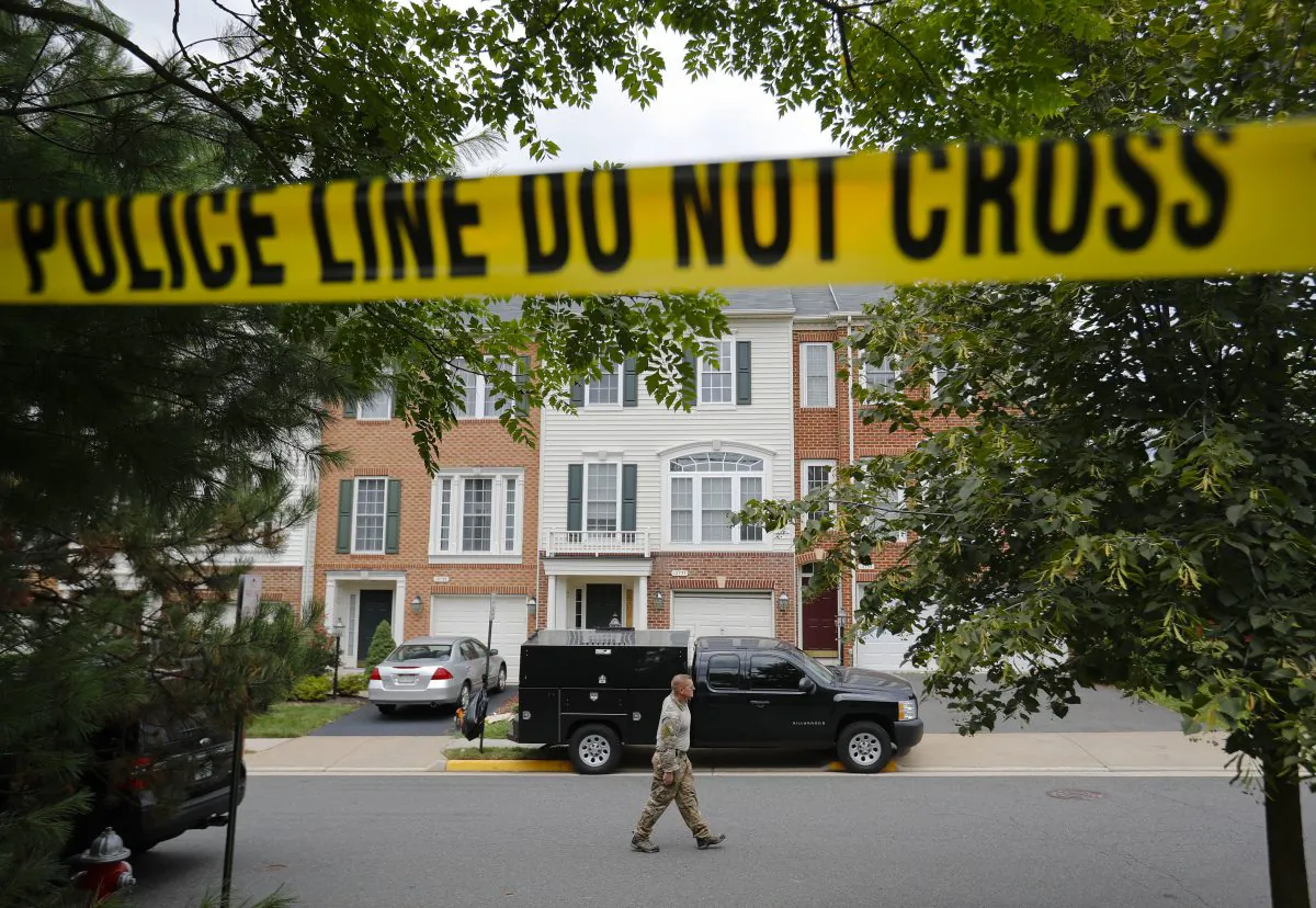 A law enforcement officer walks on the street outside the home of Nicholas Young, a Washington Metro Transit Officer, Wednesday, Aug. 3, 2016, in Fairfax, Va., Young was arrested at Metro's headquarters in Washington and charged with a single count of attempting to provided material support to a terrorist group. (AP Photo/Pablo Martinez Monsivais)