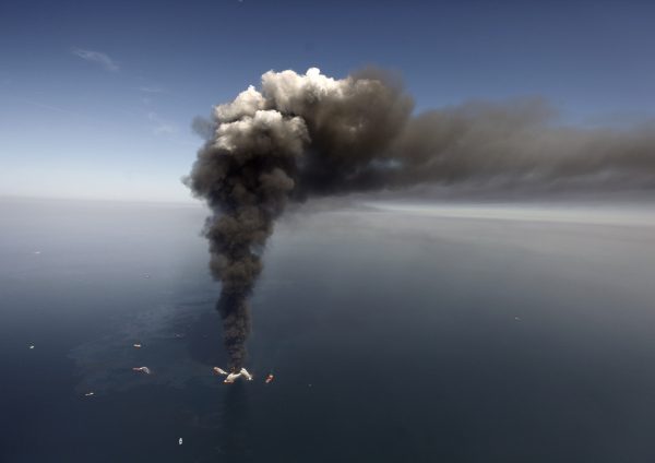 Oil can be seen in the Gulf of Mexico, more than 50 miles southeast of Venice on Louisiana's tip, as a large plume of smoke rises from fires on BP's Deepwater Horizon offshore oil rig on April 21, 2010. (AP Photo/Gerald Herbert)