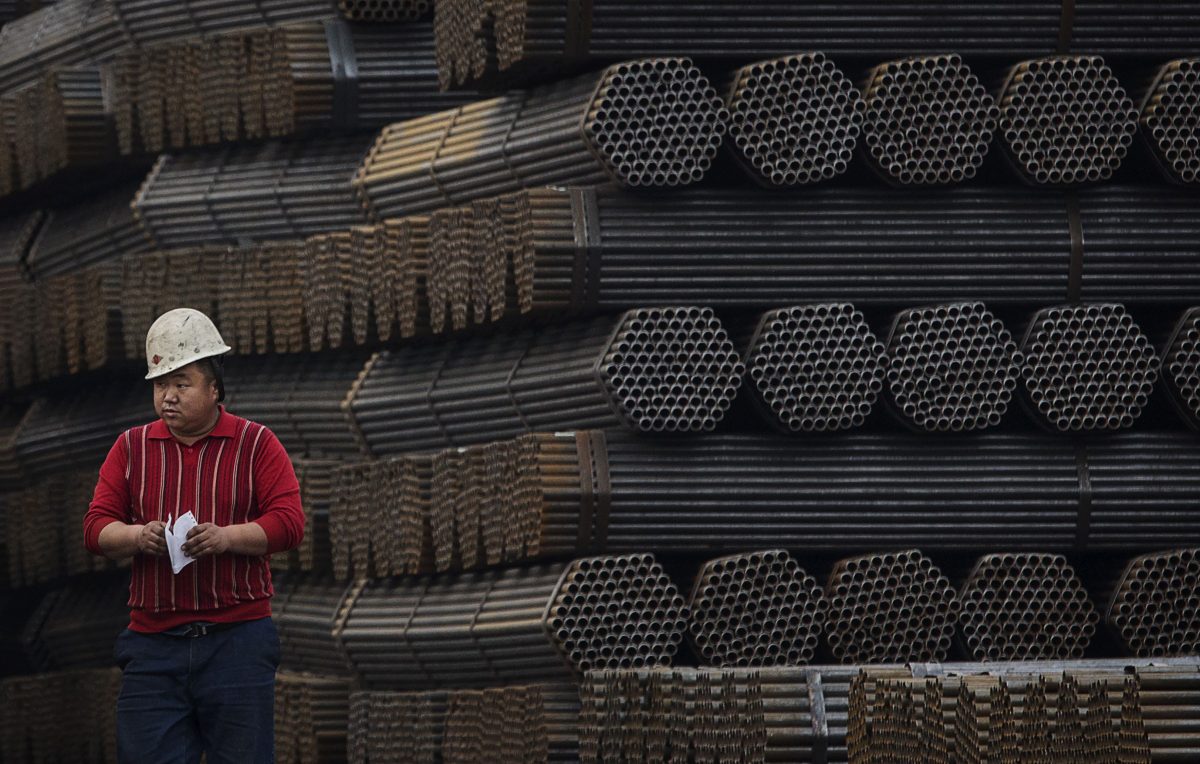 A Chinese steelworker walks past steel rods at a factory in Tangshan, in China's Hebei province, on April 6, 2016. (Kevin Frayer/Getty Images)