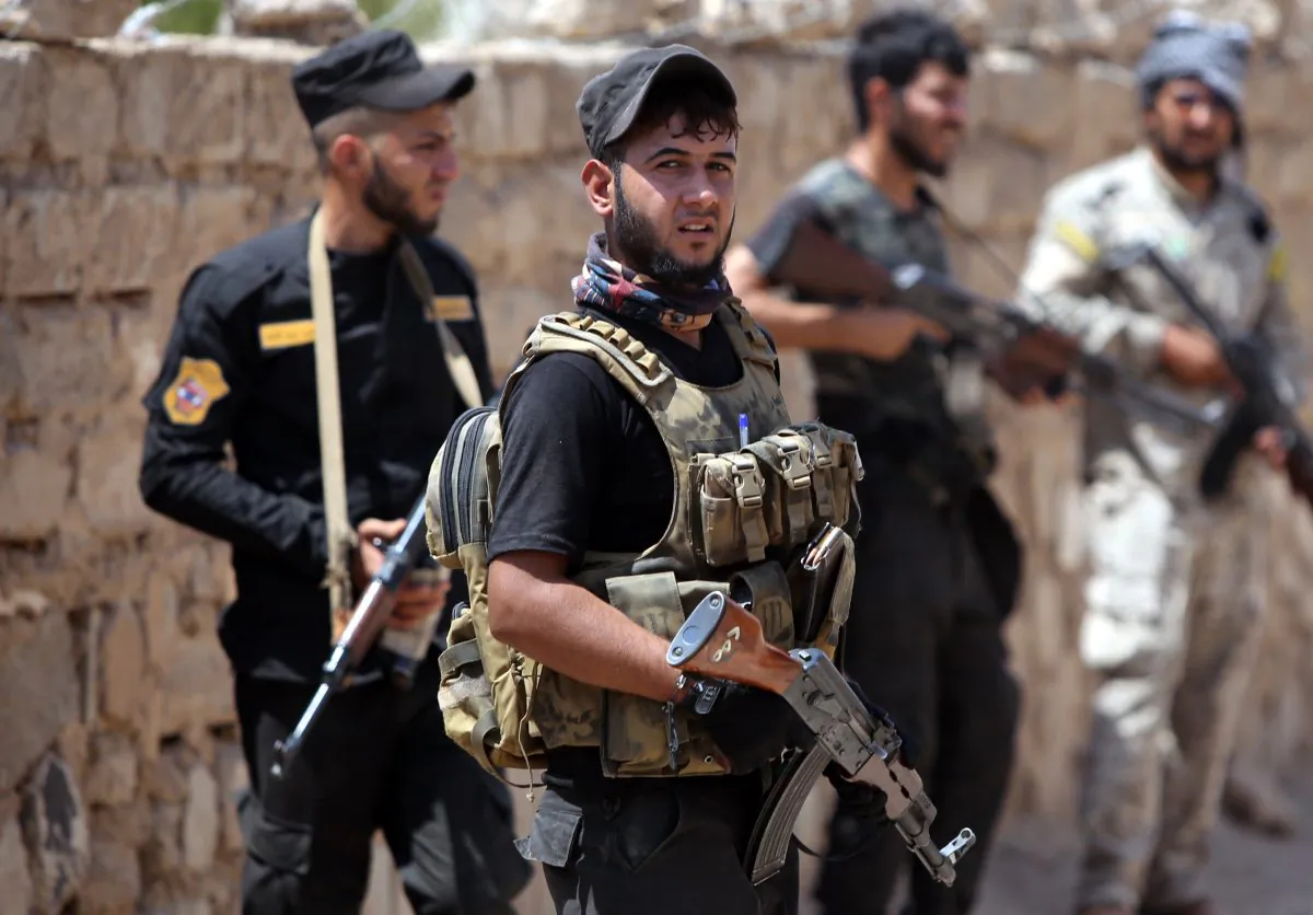 Iraqi fighters from the Shiite popular mobilisation unit hold their weapons in the outskirts of Baiji refinery north of Tikrit on May 25, 2015. (AHMAD AL-RUBAYE/AFP/Getty Images) (Photo credit should read AHMAD AL-RUBAYE/AFP/Getty Images)