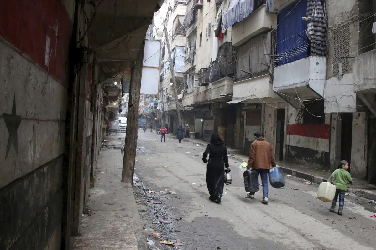 In this Feb. 11, 2016, file photo, civilians walk with containers for fuel and water in Aleppo, Syria. Syrian rescue worker says three civilians, a mother and two children, died in a suspected chlorine gas attack on an opposition-held district in the city of Aleppo. The report, which was posted online on Thursday, Aug. 11, could not be independently verified and it was not clear how it was determined that chlorine gas was released. (Alexander Kots/Komsomolskaya Pravda via AP, File)
