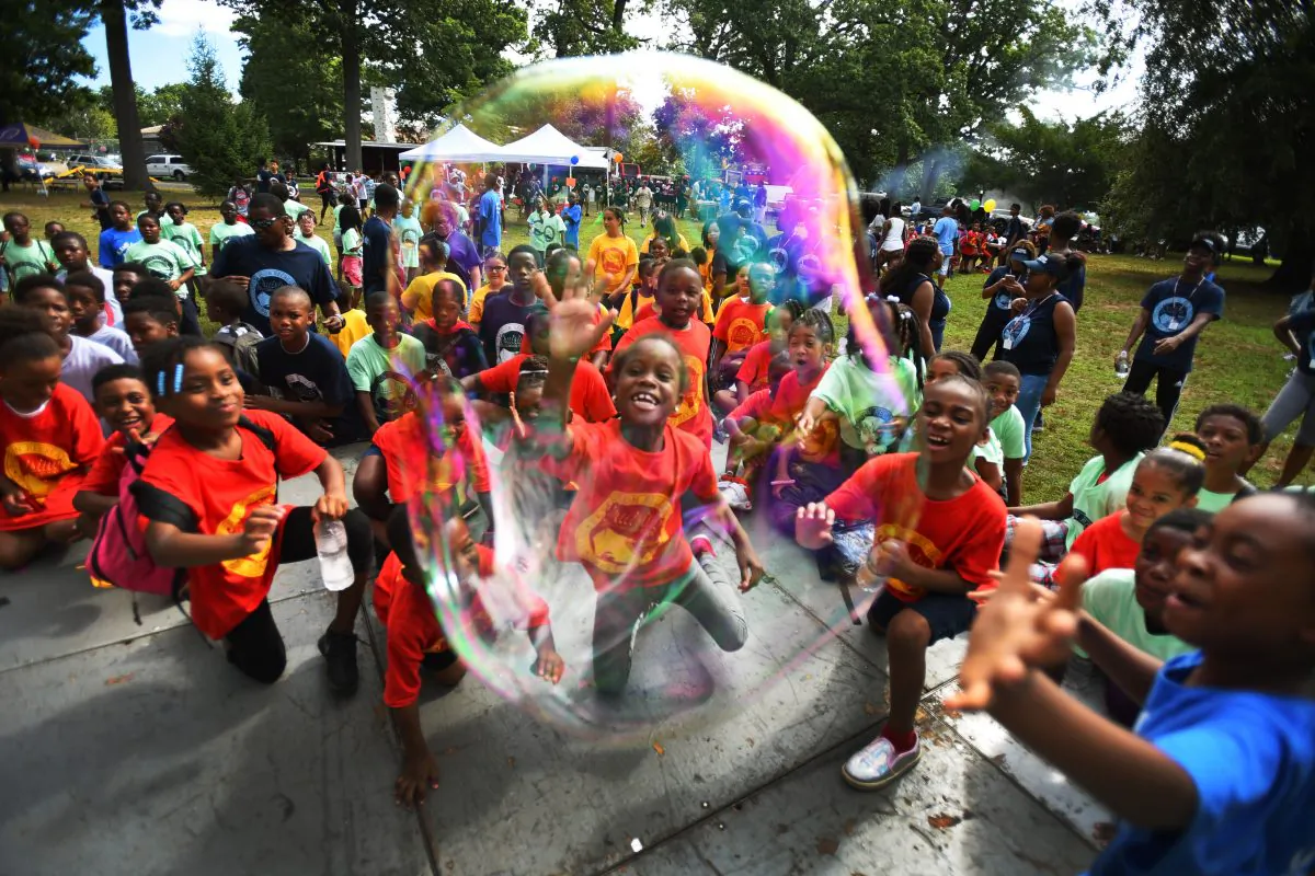 Children try to grab a giant soap bubble during the annual "Day in the Sun" end of summer camp at Eastside Park in Paterson, N.J., on Aug. 11, 2016. (Mitsu Yasukawa/The Record of Bergen County via AP)