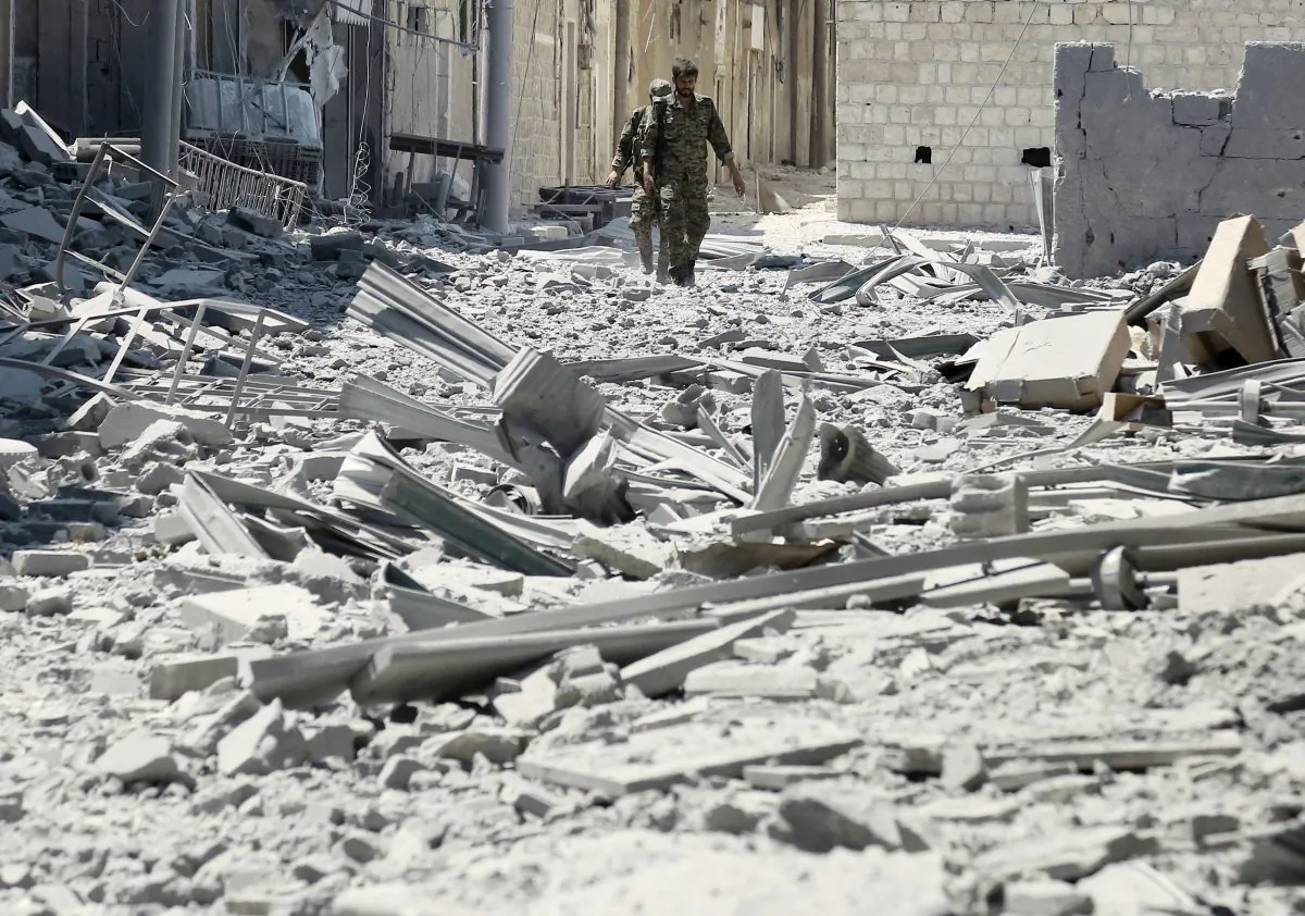 Members of the Syrian Democratic Forces (SDF) walk amidst the rubble of destroyed buildings in the northern Syrian town of Manbij on Aug. 7, 2016. (Delil Souleiman/AFP/Getty Images)