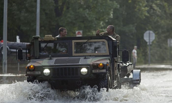 Army National Guard vehicles travel through floodwaters, Sunday, Aug. 14, 2016, on LA-442, west of Tickfaw, La., as rescue operations continue after heavy rains inundated the region. (AP Photo/Max Becherer)