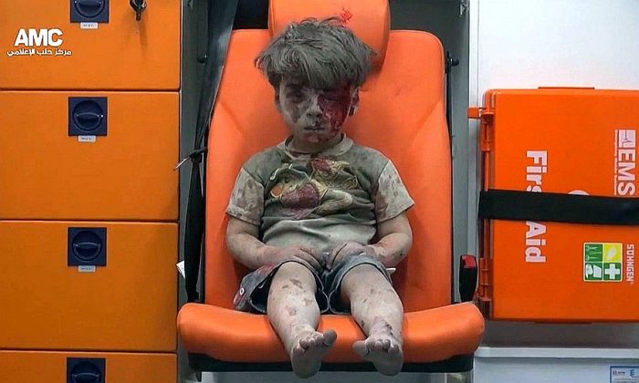 In this frame grab taken from video provided by the Syrian anti-government activist group Aleppo Media Center (AMC), a child sits in an ambulance after being pulled out or a building hit by an airstirke, in Aleppo, Syria, Wednesday, Aug. 17, 2016. Syrian opposition activists reported an airstrikes on the al-Qaterji neighborhood in Aleppo late Wednesday. (Aleppo Media Center via AP)