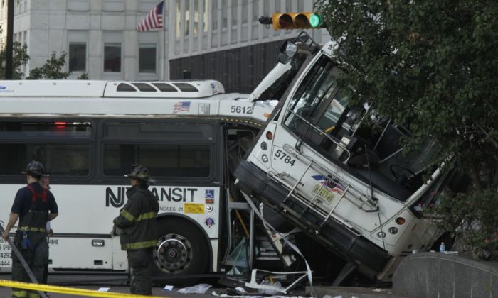 Emergency crews respond to the scene of a accident involving two commuter buses in Newark, N.J., on Friday, Aug. 19, 2016.  Investigators are trying to determine if a commuter bus ran a red light and broadsided another commuter bus, killing a driver and injuring several.   (Bob Sciarrino/NJ Advance Media via AP)