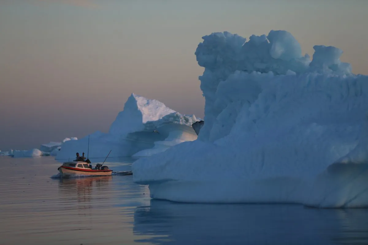 A fishing boat navigates past icebergs that broke off from the Jakobshavn Glacier in Ilulissat, Greenland on July 23, 2013. (Joe Raedle/Getty Images)