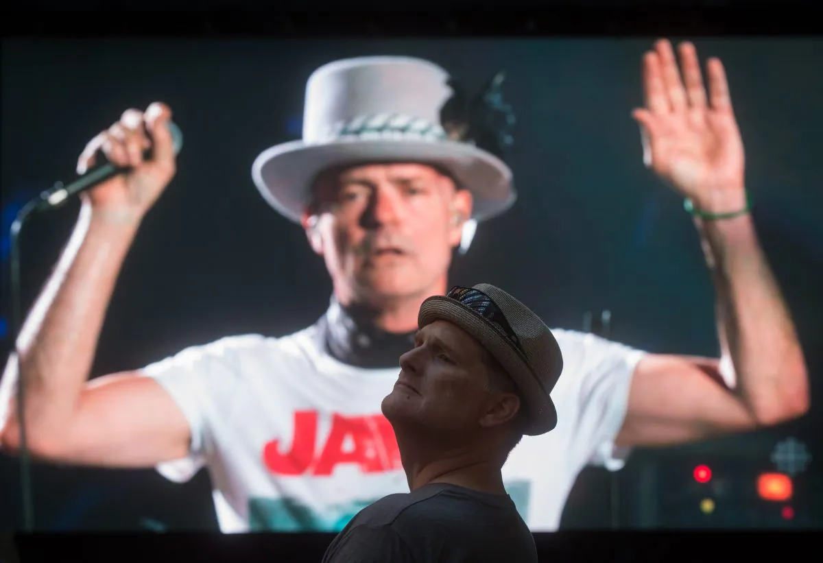 Lead singer Gord Downie is seen performing on a screen as a man watches during a viewing party for the final stop in Kingston, Ontario, from Vancouver, British Columbia, Saturday Aug. 20, 2016. The Tragically Hip mixed fan favourites, newer songs and some politics on Saturday night during the final show of their "Man Machine Poem" tour. (Darryl Dyck/The Canadian Press via AP)