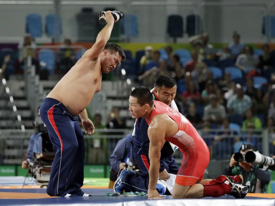 Coaches for Mongolia's Mandakhnaran Ganzori, at right, strip in protest after a loss to Uzbekistan's Ikhtiyor Navruzov during the men's 65-kg freestyle bronze medal wrestling match at the 2016 Summer Olympics in Rio de Janeiro, Brazil, Saturday, Aug. 20, 2016. (AP Photo/Marcio Jose Sanchez)