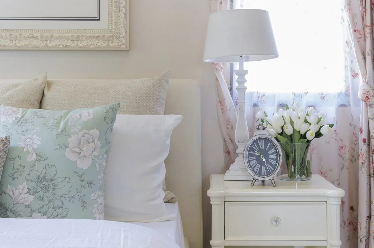 A feminine cottage style bedroom with romantic soft floral print curtains and pillows. (KhongkitWiriyachan/iStock)