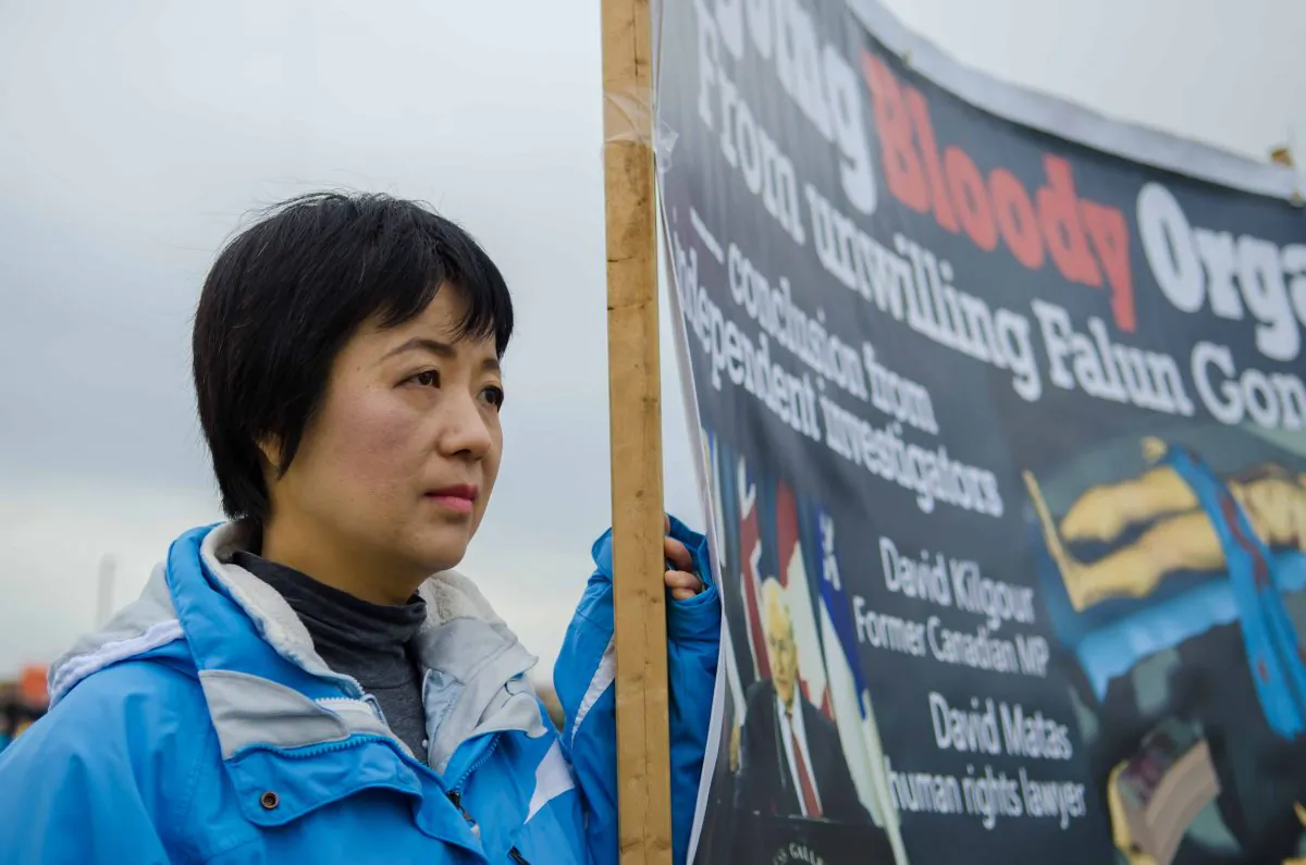 Michelle Zhang holds a banner against forced organ harvesting in China during a rally on Parliament Hill on Nov. 4, 2014. Zhang’s sister, who practiced Falun Gong, disappeared in 2002. Her brother-in-law died in prison, his body cremated without the family's permission. (Matthew Little/Epoch Times)