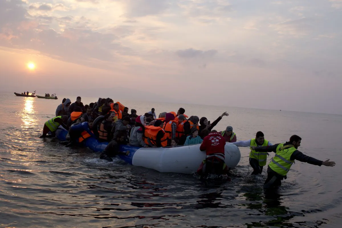 Volunteers help migrants and refugees on a dingy as they arrive at the shore of the northeastern Greek island of Lesbos, after crossing the Aegean sea from Turkey on March 20, 2016. (AP Photo/Petros Giannakouris)