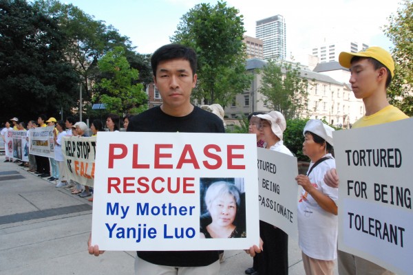 Wenta Fan holds a sign with a portrait of his mother, Yanjie Luo, who in 2011 was sentenced to 13 years in prison in China for practising Falun Gong, outside Toronto City Hall on Aug. 25, 2016. Fan was among the Falun Gong adherents at the event to appeal to Prime Minister Justin Trudeau for help to stop the persecution of their spiritual discipline in China and to seek the release of 12 family members with Canadian ties jailed in China for practising Falun Gong. (Yi Ling/Epoch Times)